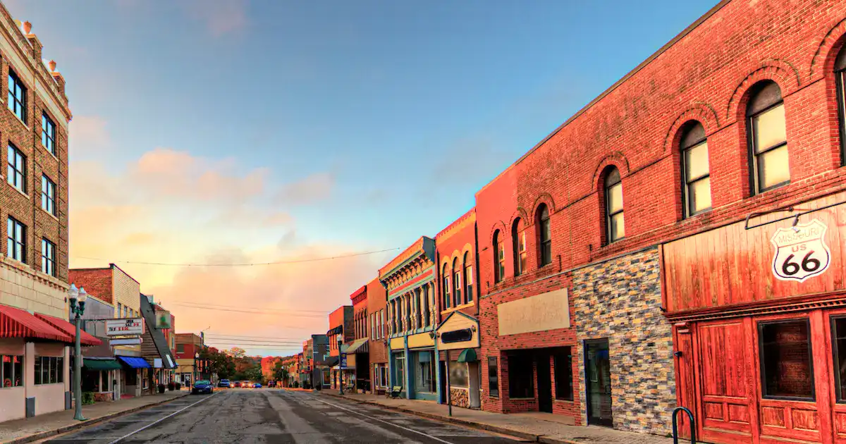 A bustling small-town Main Street with historic brick buildings and colorful storefronts.