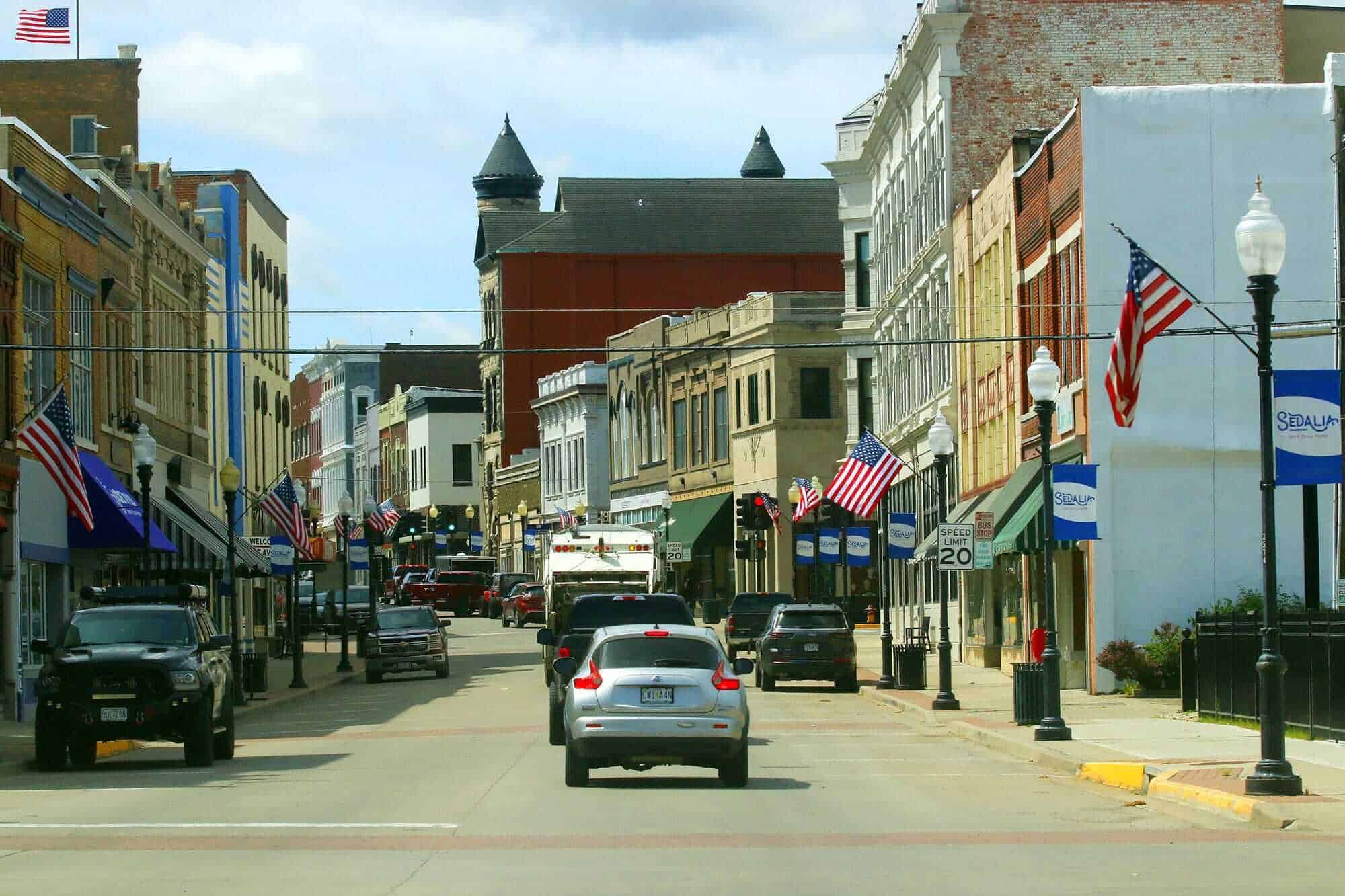 A bustling downtown street with historic buildings and American flags, showcasing small-town charm a.