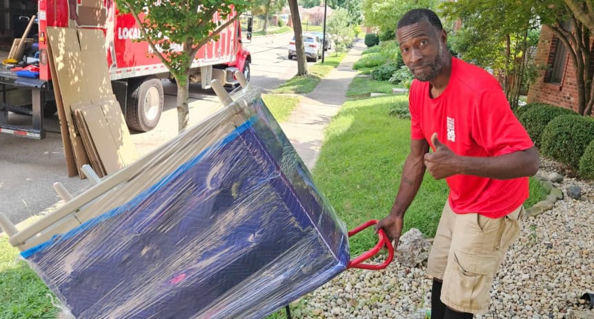 Man performing a simple move with a large item on a dolly outside.