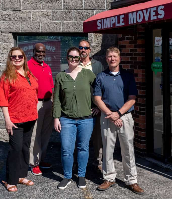 Group of diverse professionals standing outside Simple Moves store on a sunny day.
