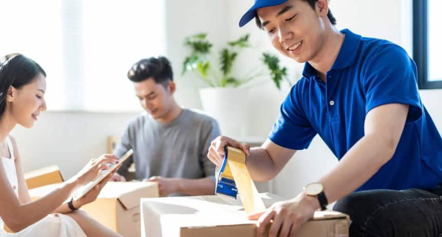 Efficient packing tips for a smooth move, featuring a young man packing boxes with a smile, in a bri.